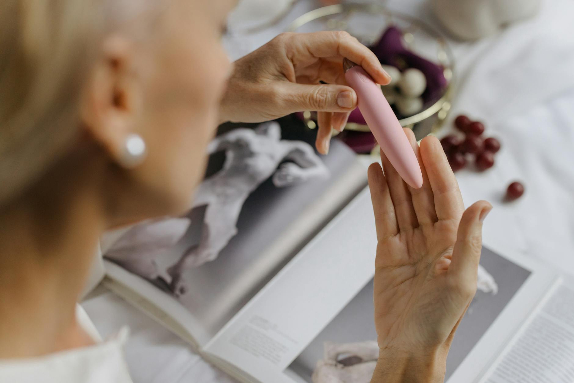 A woman holding a pink vibrator near art books, illustrating intimate exploration without penetration