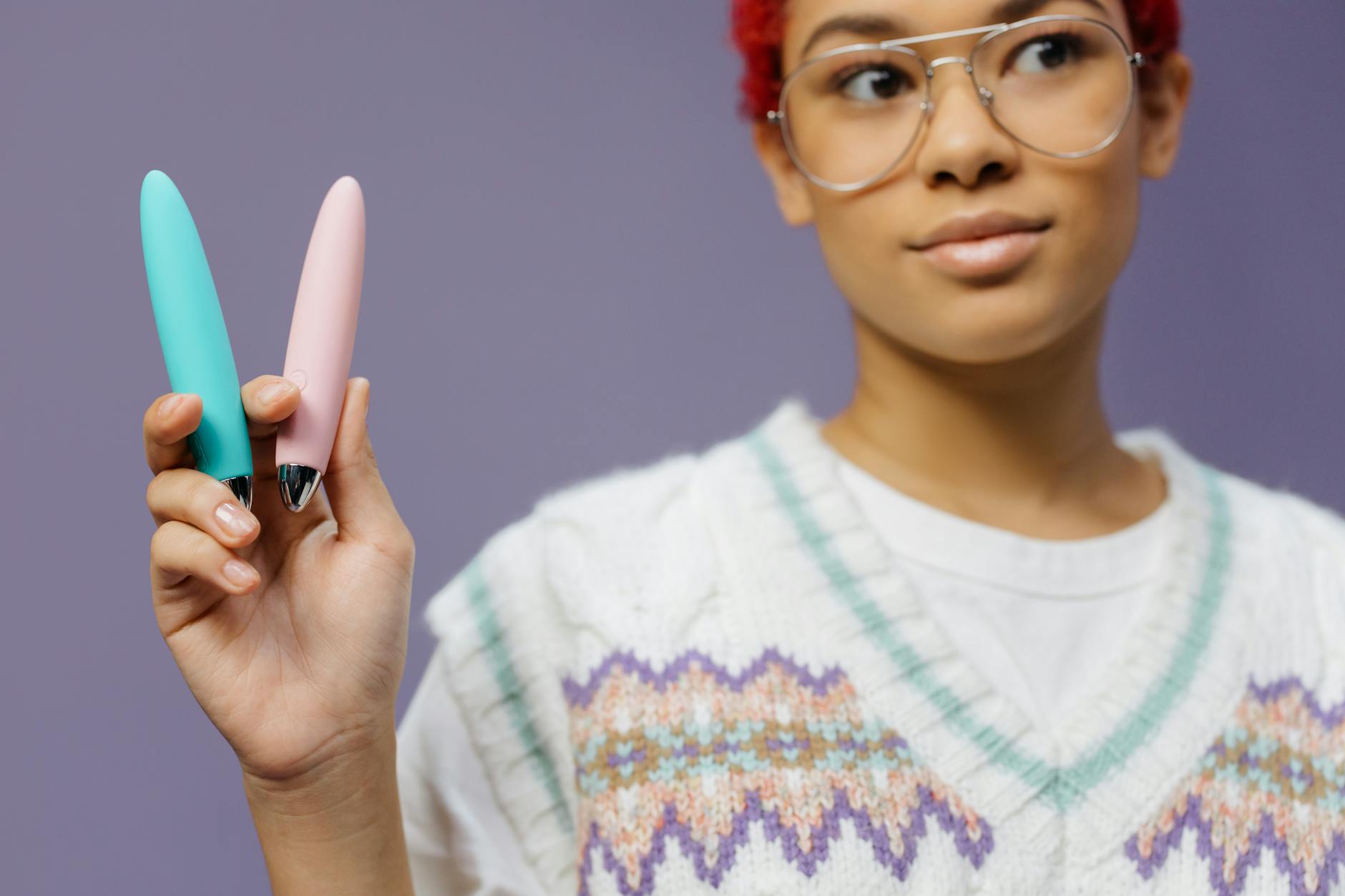 A close-up of hands holding a blue personal massager against a knitted sweater, symbolizing comfort and slower-paced intimacy after 40.