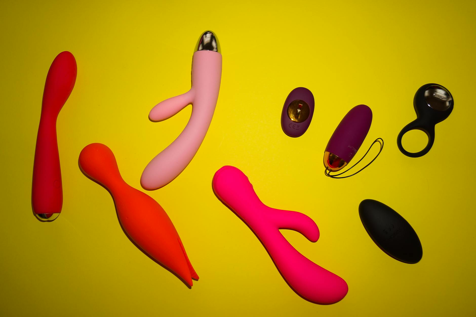Close-up of a hand holding an orange vibrator against a minimalistic purple backdrop, showcasing modern sensuality.